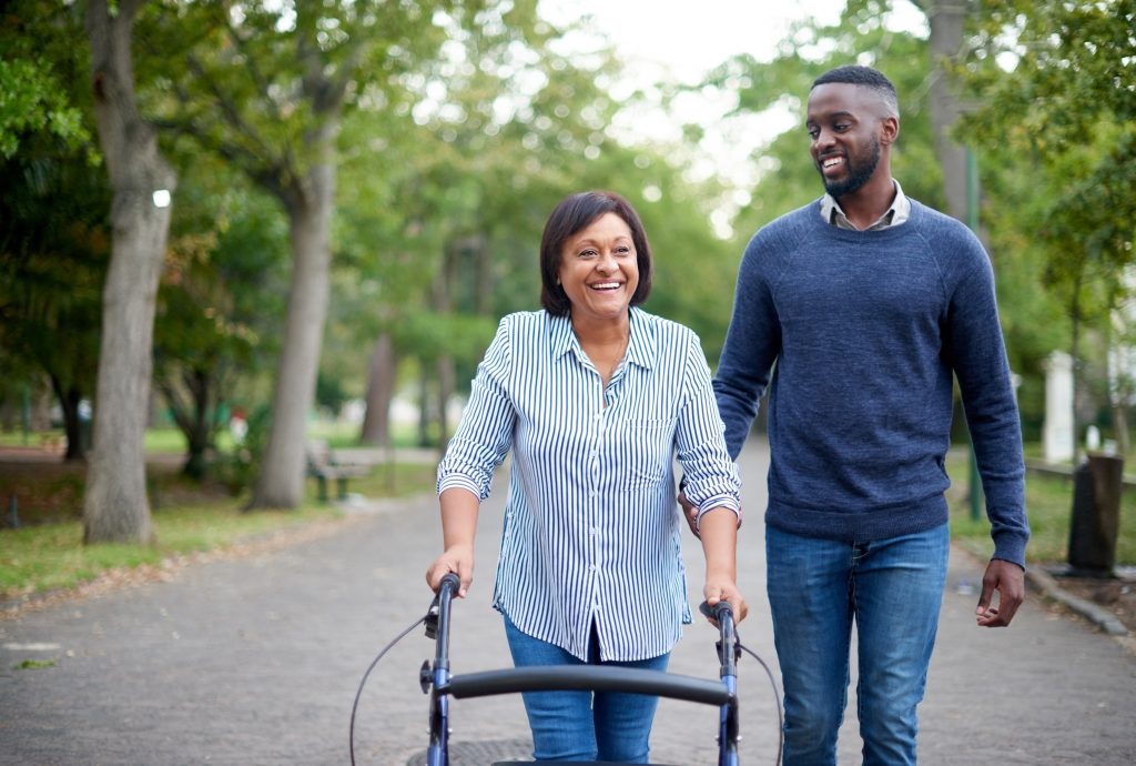 Cropped shot of a happy mature woman using a walker while a handsome young man assists her in the park