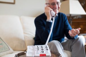 Senior Man Using Telephone With Oversized Keypad At Home